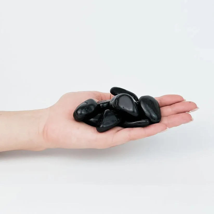 Glossy jet black polished pebbles held in an open hand