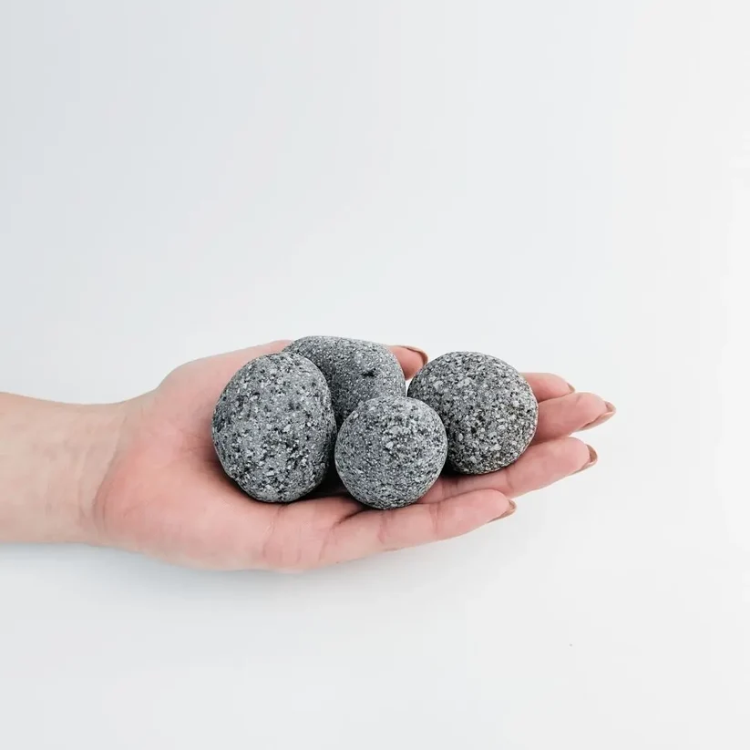 Rounded speckled grey black lava stones in a hand