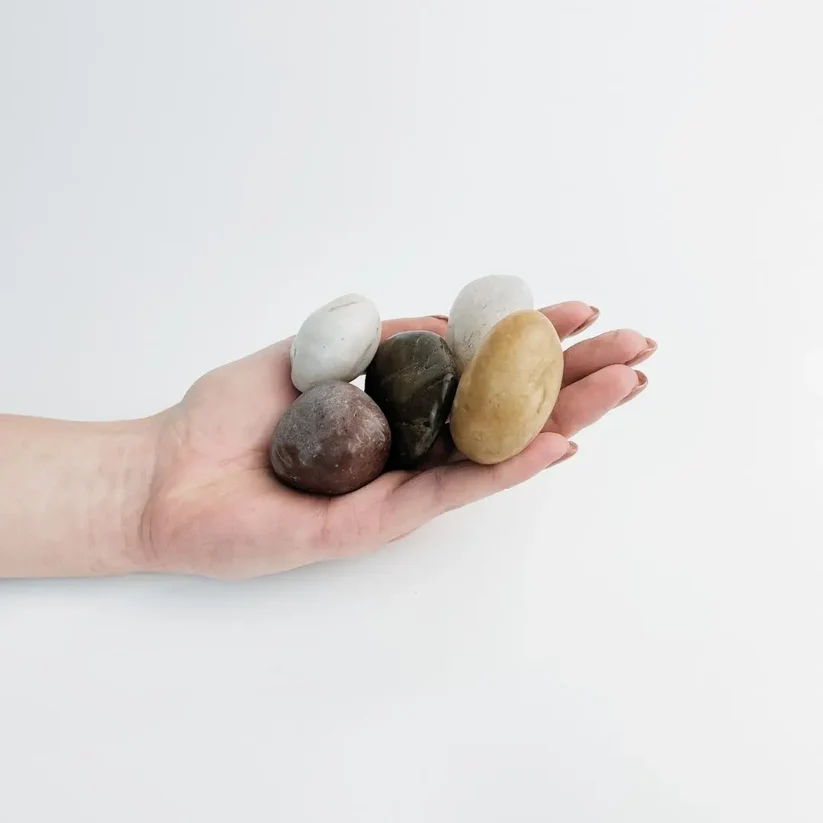 Mixed grey, brown and cream high-polished pebbles held in an open hand