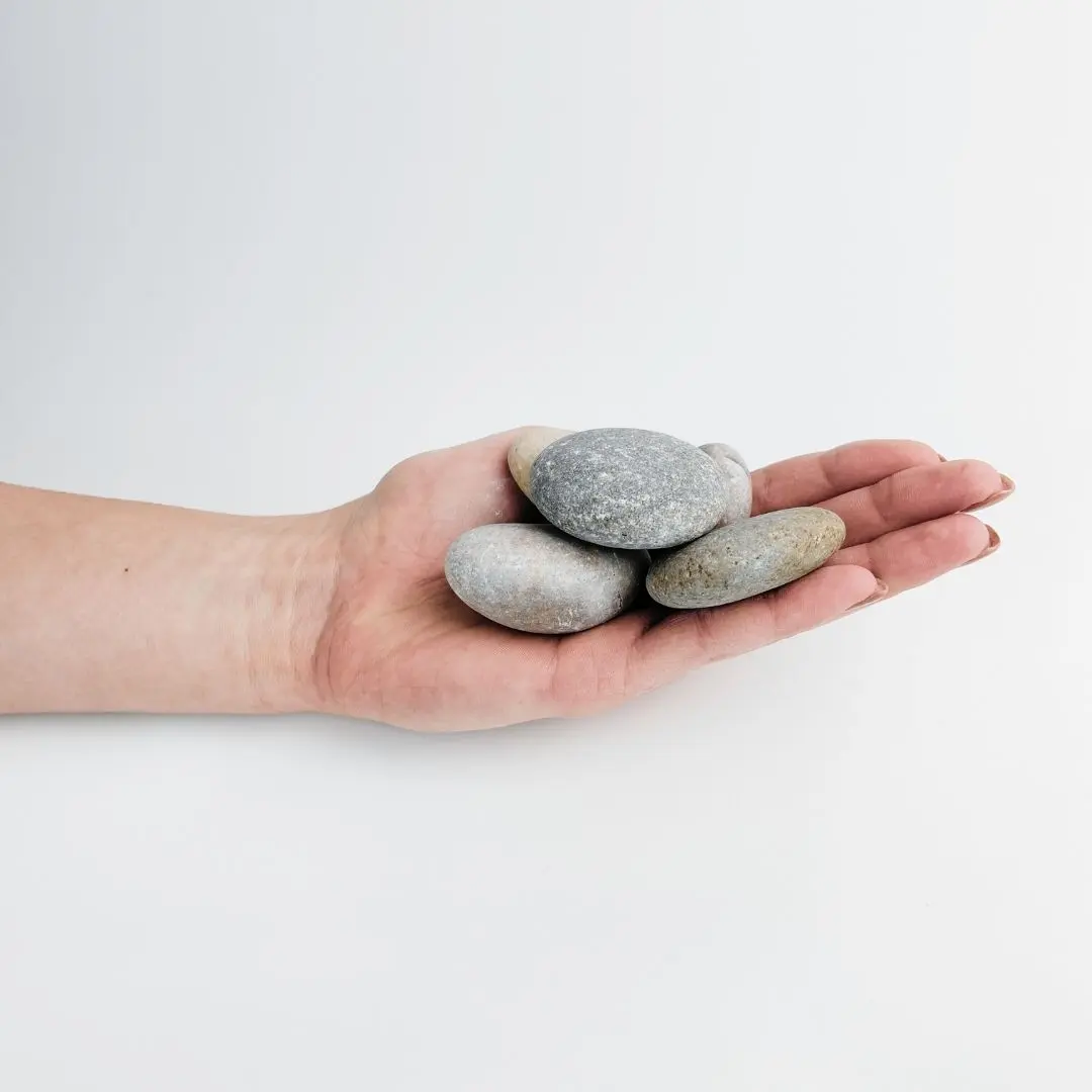 Smooth grey and beige Japanese pebbles resting on a palm