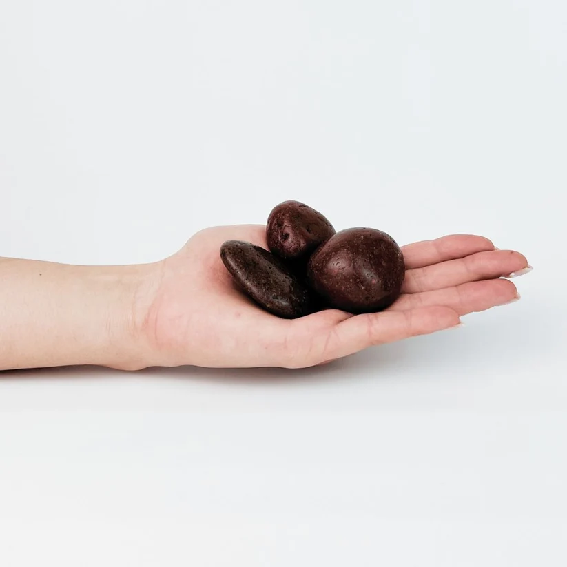 Deep maroon polished pebbles in an open hand