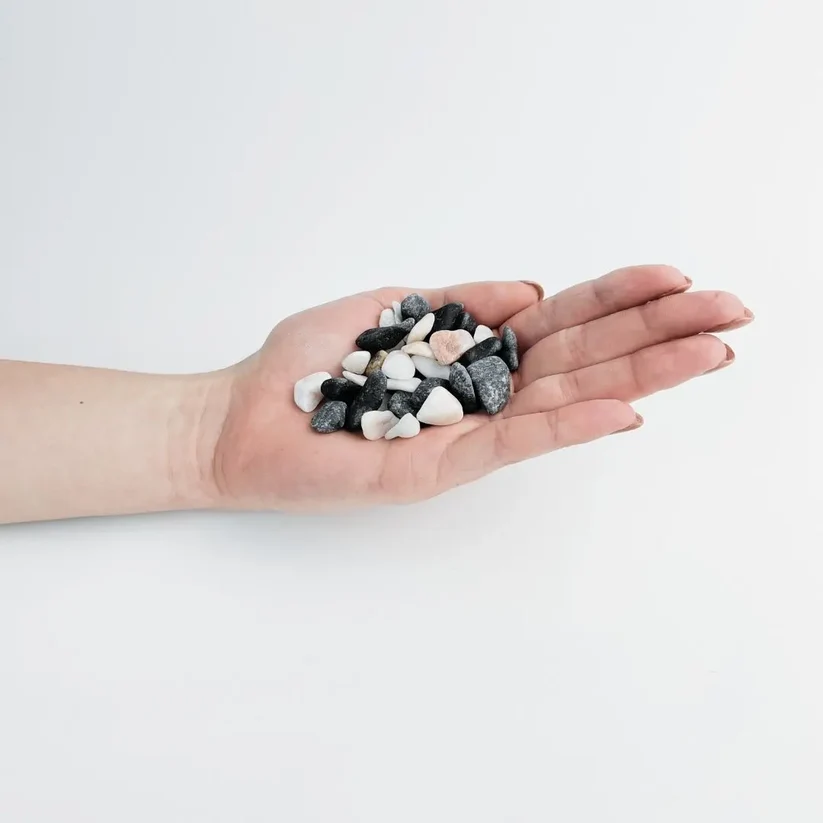 Small black, white and pale pink panda pebbles in a palm