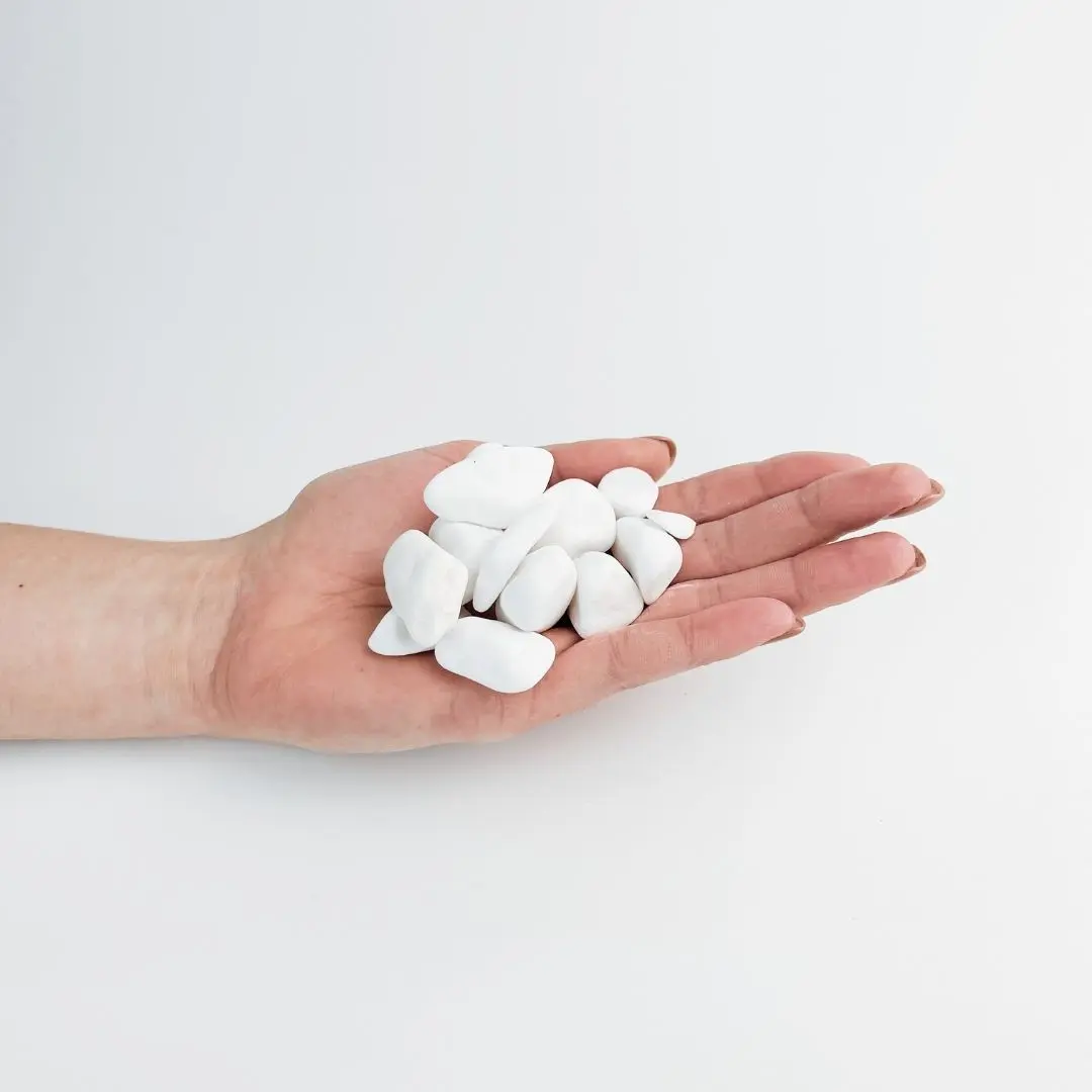Bright snow white Thassos marble pebbles in an open palm